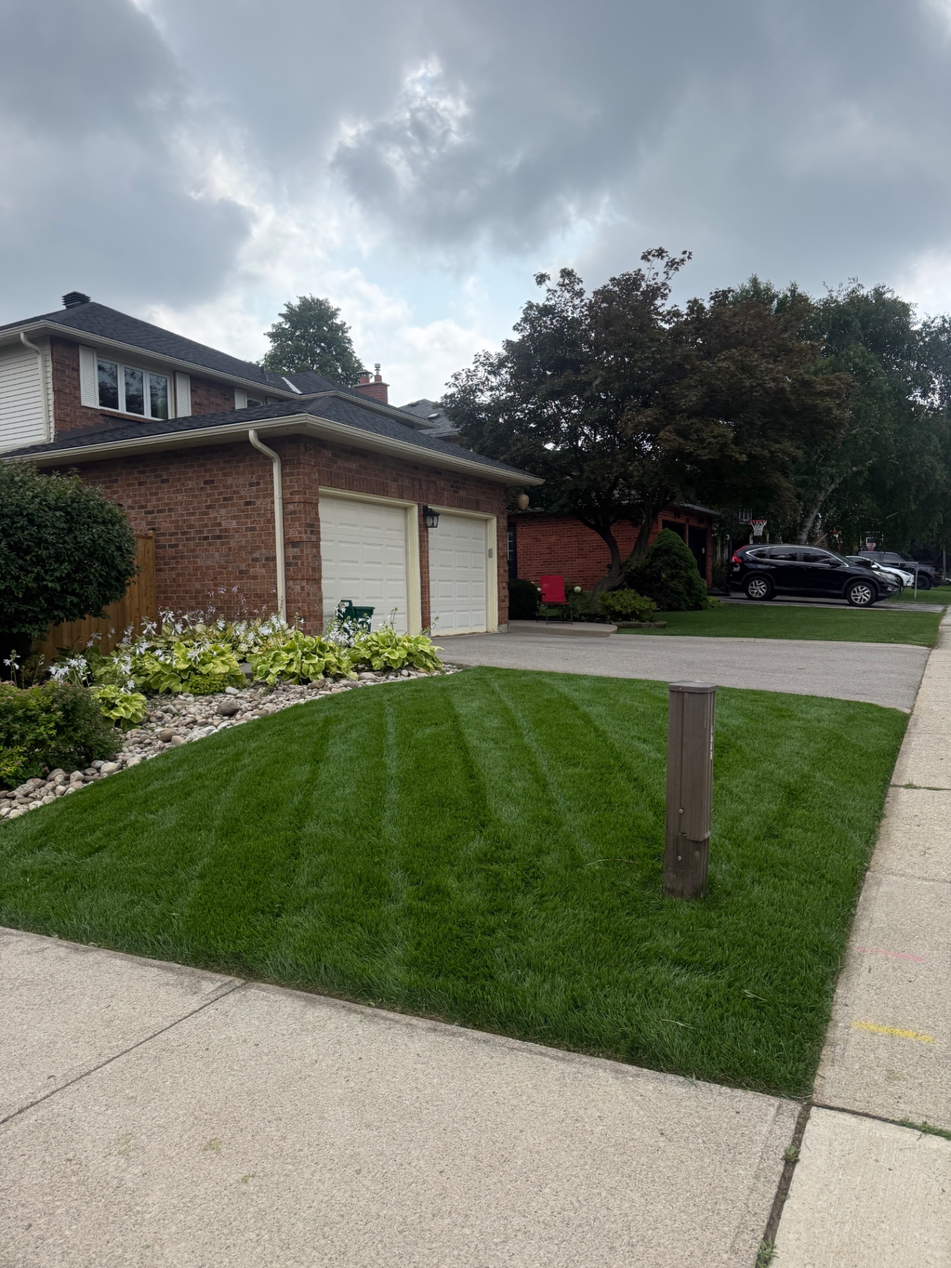 Striped front lawn with river-rock garden bed in Burlington