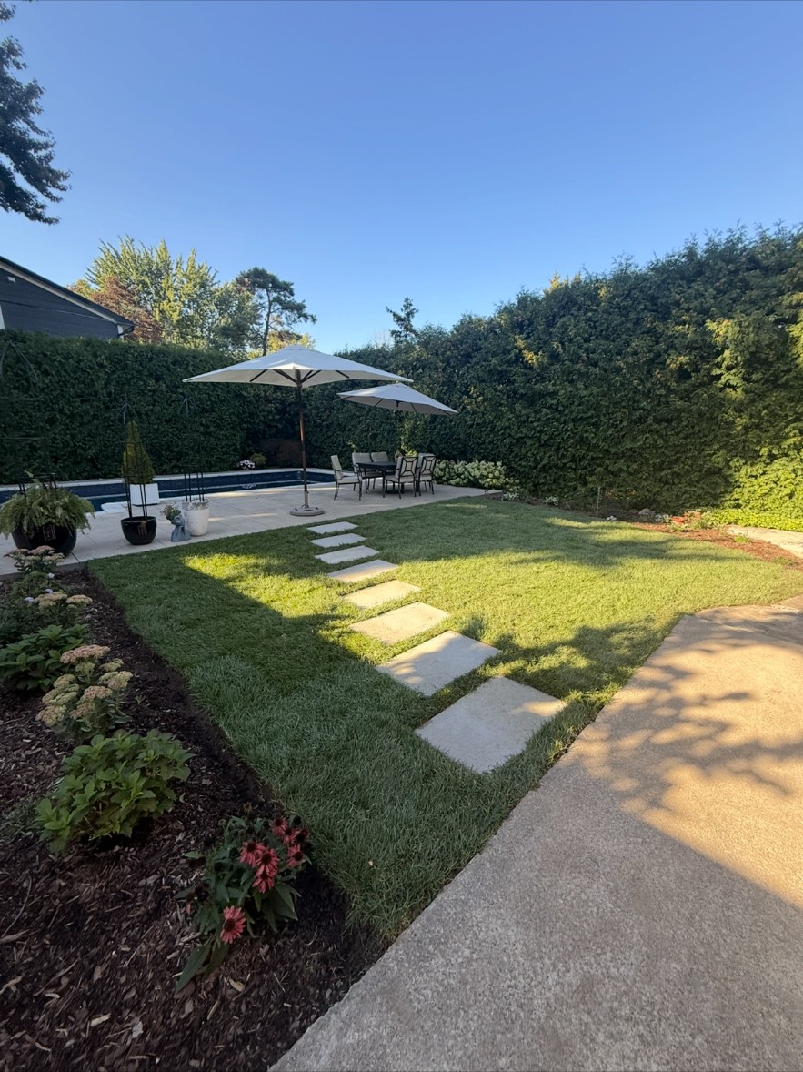 Backyard with new sod, stepping-stone walkway, and garden beds installed by CBR Property Care