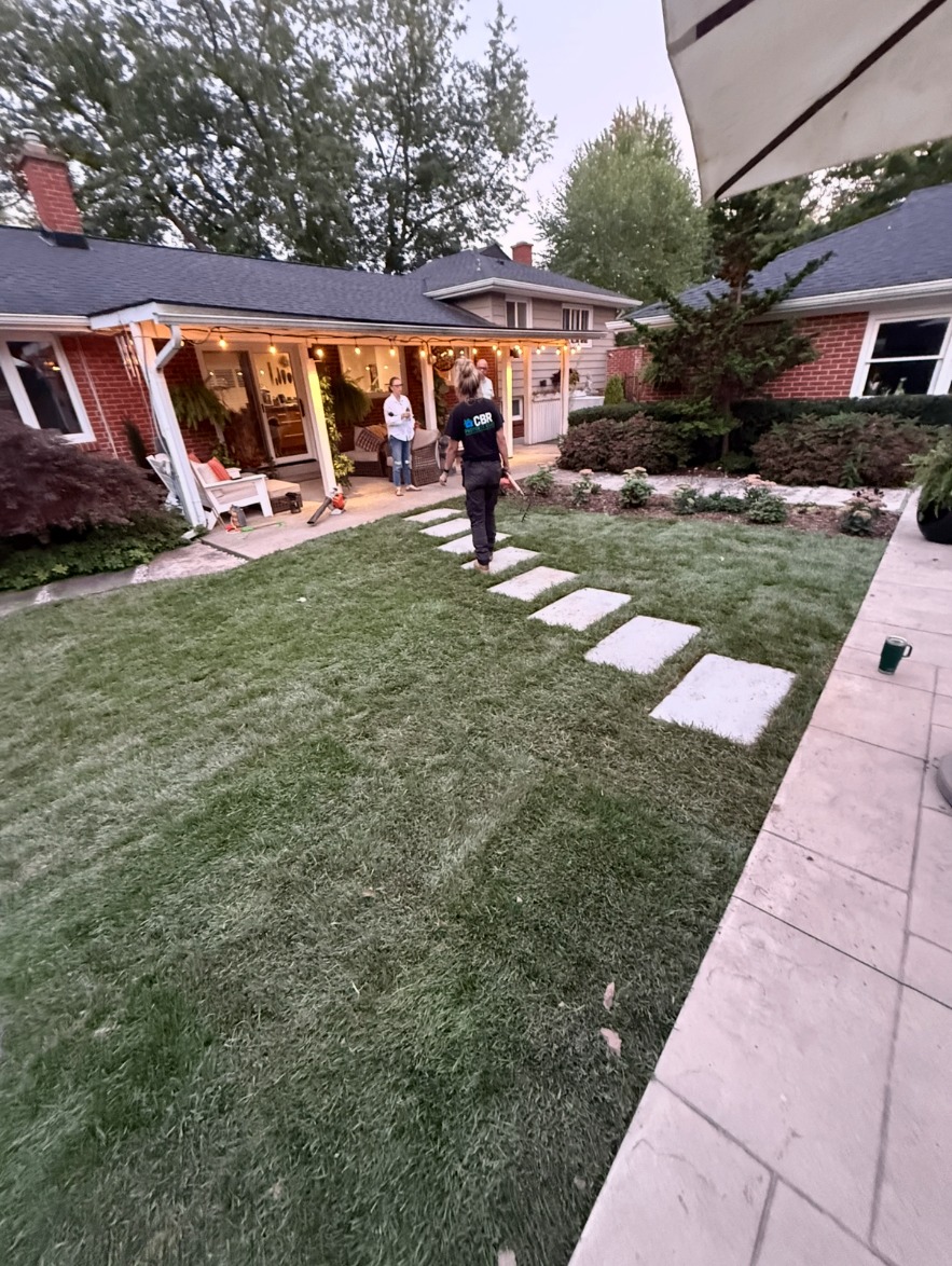 Stone paver walkway across a backyard lawn at dusk