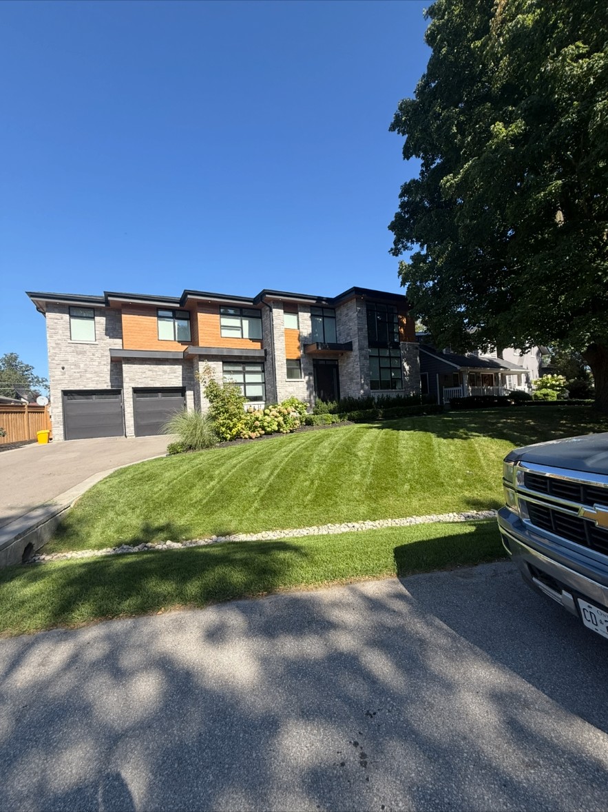 Freshly mowed front lawn with river-rock border and CBR truck at the curb