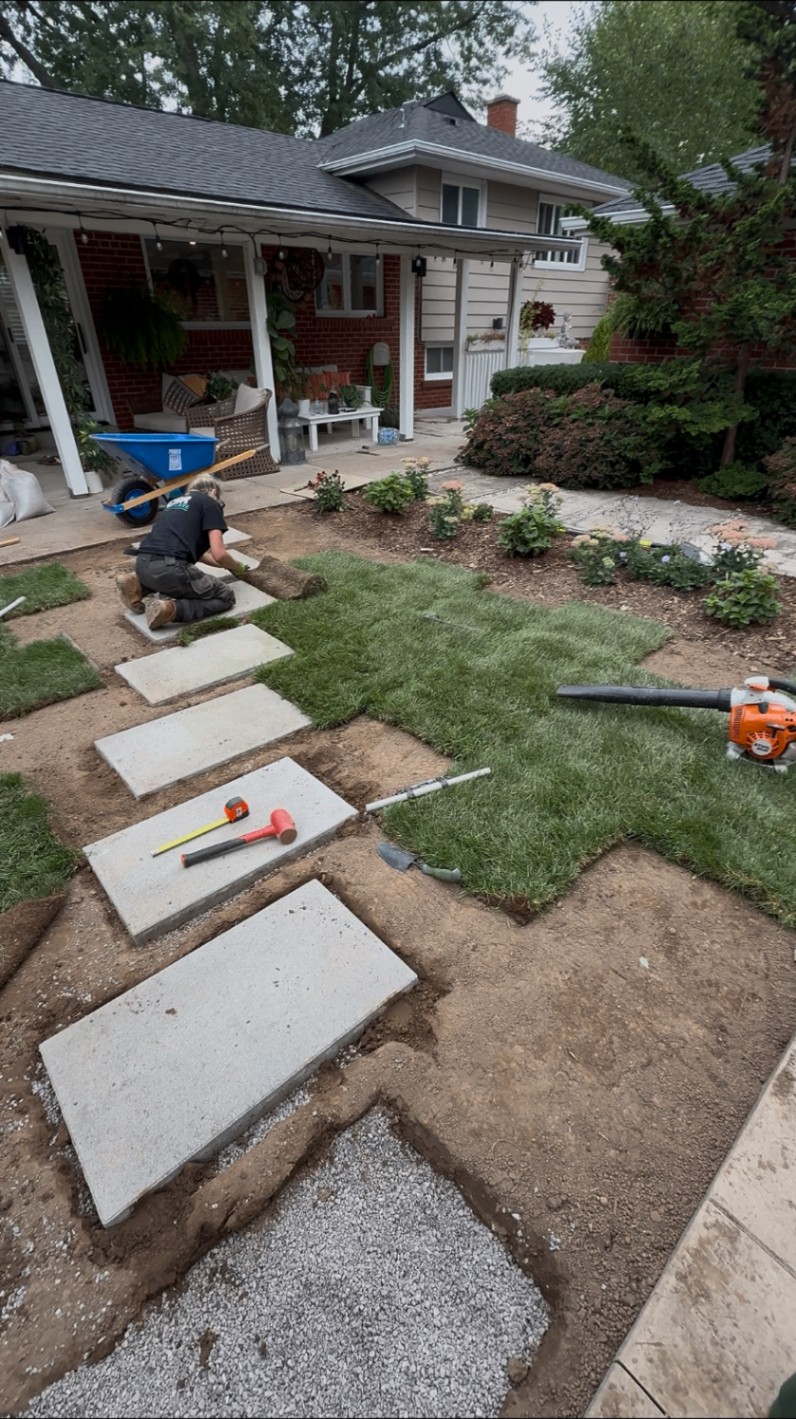 Concrete slab stepping stone path being set alongside fresh sod
