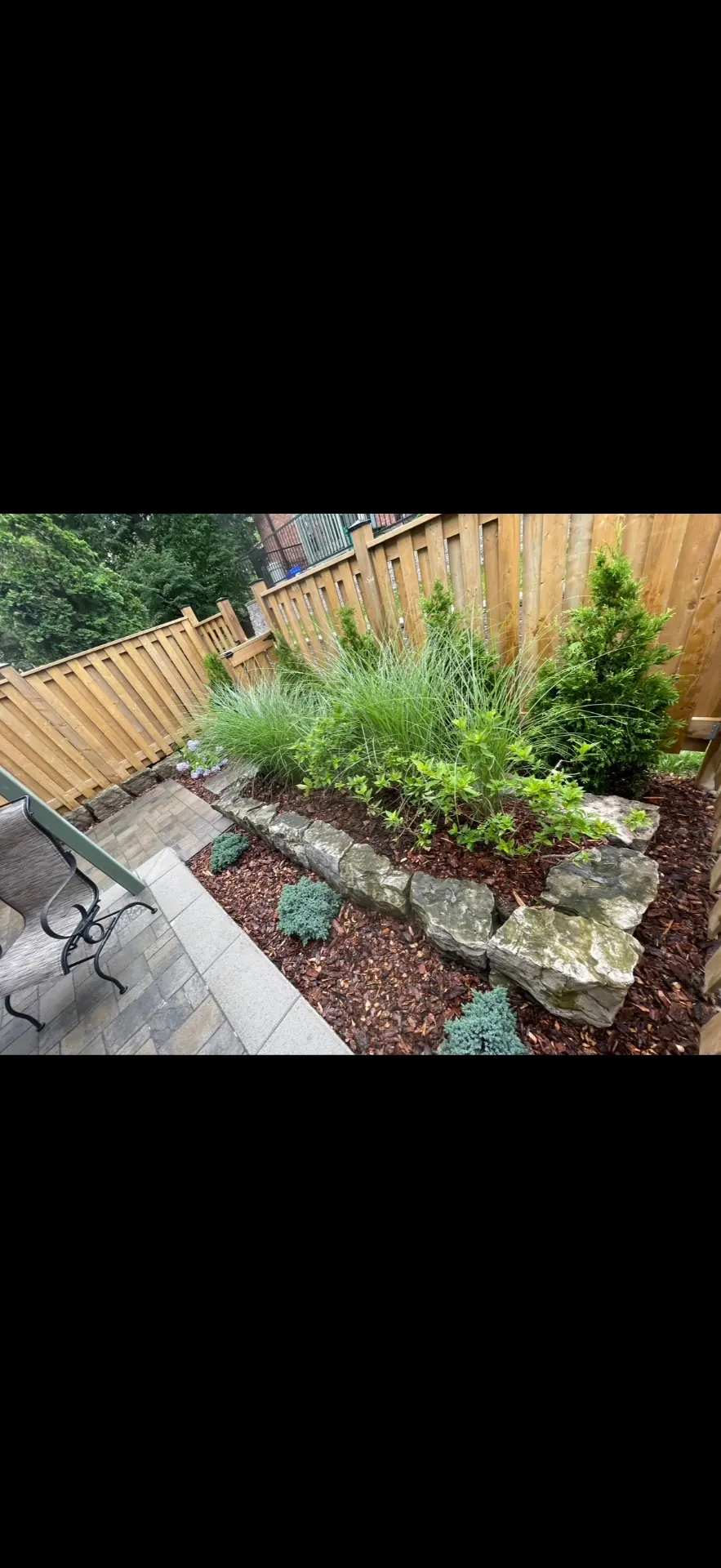 Custom garden bed with stone edging and mulch